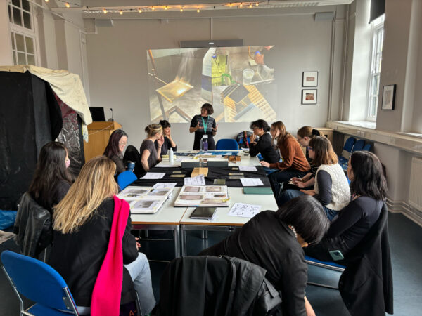 a group of students seated at a large table looking at a lecturer