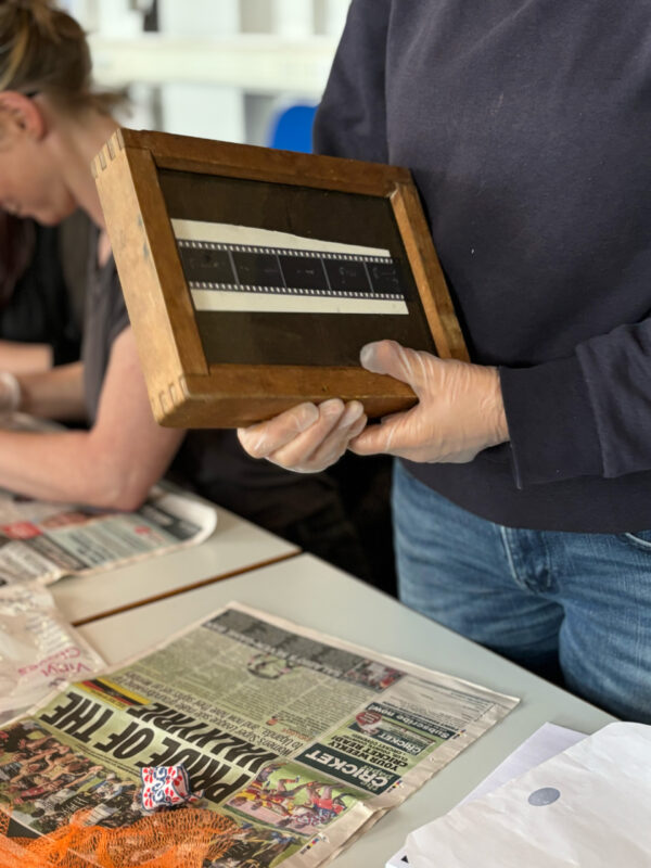 a hand holds a wood and glass box used to hold developing photographs